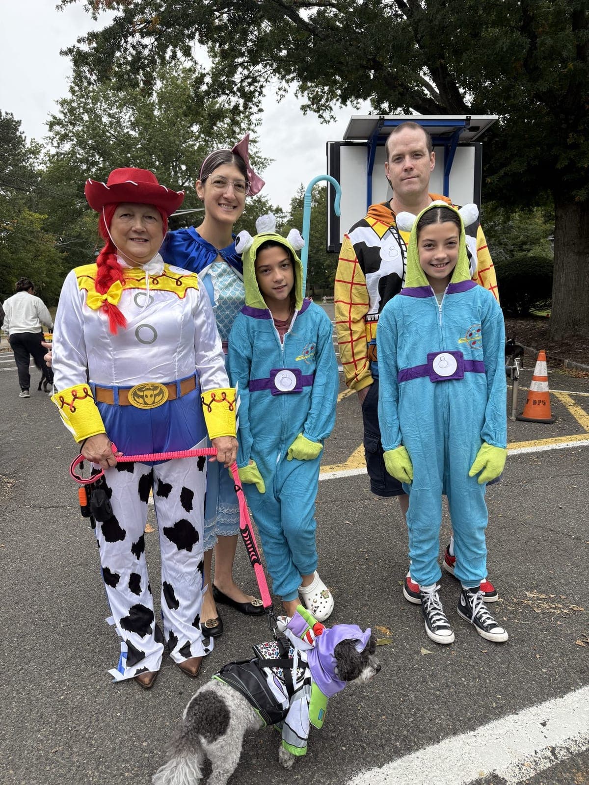 A Toy Story themed family, pup included, poses at Fan WOOF Day.
