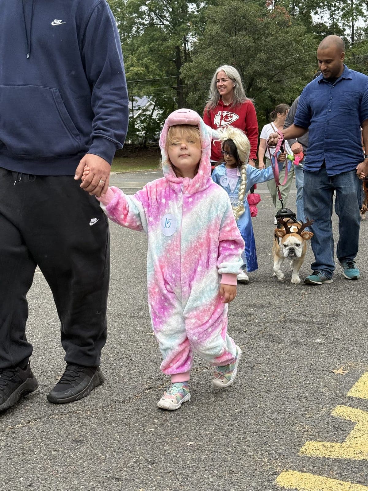 A young parade-goer in a pastel costume strolls along with the crowd.