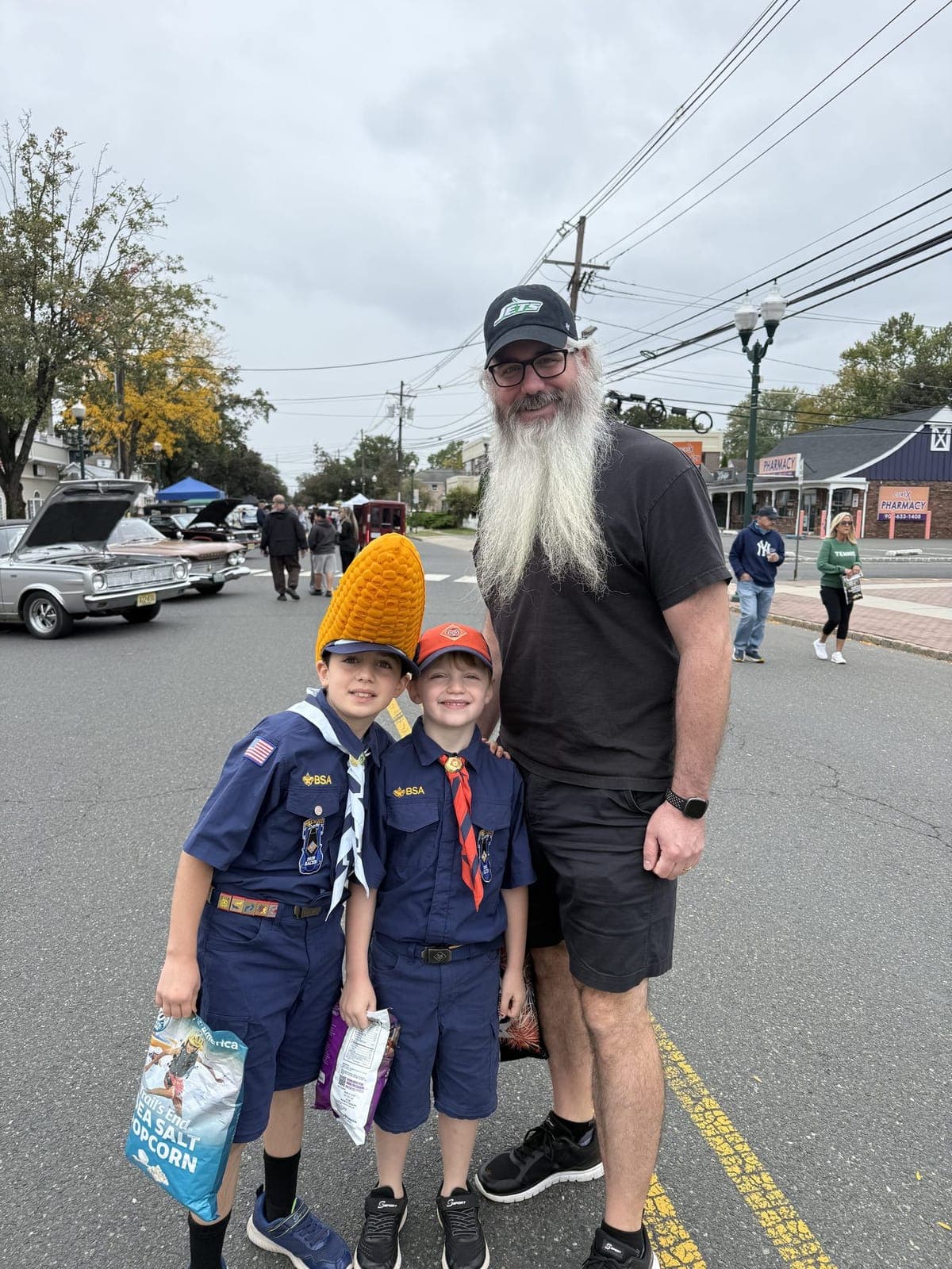 Cub Scouts show off a few festival finds, with classic cars lining the street behind them.
