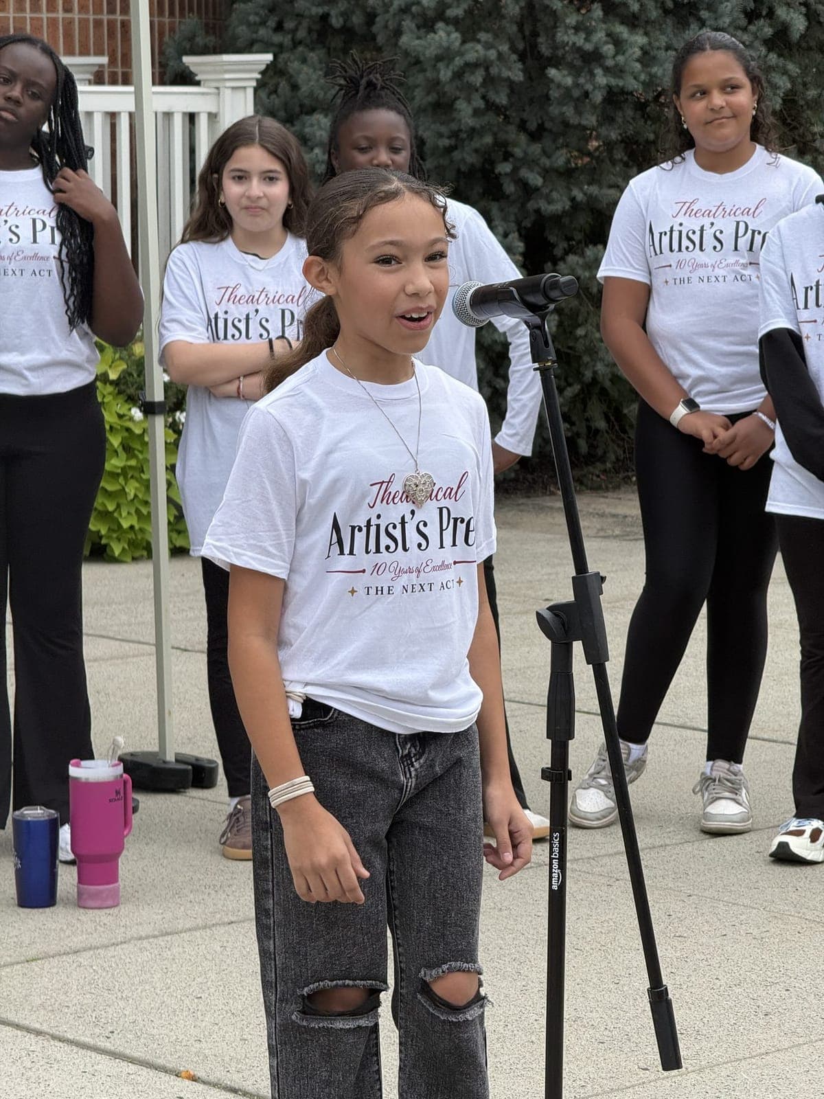 A young performer takes the microphone as her troupe looks on.
